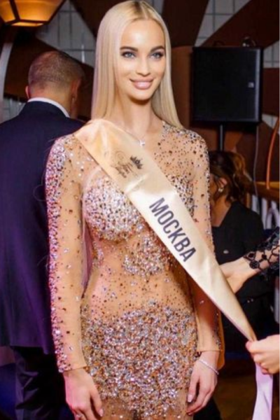 A woman in a dress holding onto a sash